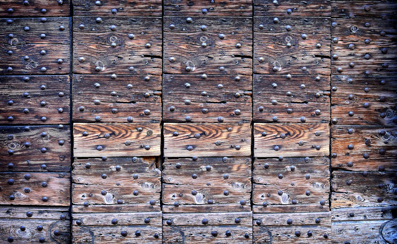Close-up of a rustic wooden plank pattern with metal rivets, showing texture.